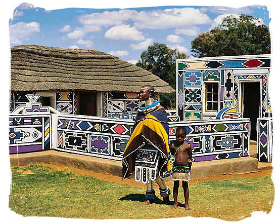 Ndebele women showing off the traditional decoration of her home