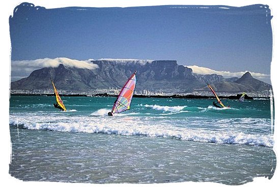 Surfers viewed from Blouberg beach, with Table Mountain as backdrop - Activity Attractions in Cape Town South Africa and the Cape Peninsula